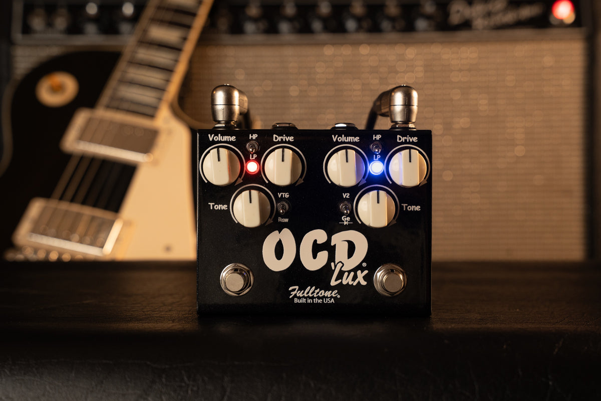 Fulltone OCD’Lux with cream controls and glowing red and blue LEDs in front of a vintage amplifier
